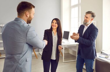Ofiste duran ve anlaşmaya sevinen üç genç iş adamından oluşan bir grup greve gitti. Erkek kadınla tokalaşırken toplantıyı bitirir, kontrat imzalar ya da yeni çalışanı selamlar..