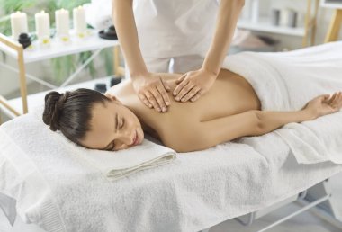 Spa salonuna giden rahat bir kadın, kanepeye uzanmış, sırt masajı yaptırıyor, gözlerini kapalı tutuyor. Bilinmeyen terapist kadın omuzlarını ovuyor, nazikçe masaj yapıyor. Stres atma kavramı 