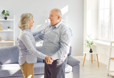 Evde mutlu son sınıf dansları, neşeli emekli eşler karı koca oturma odasında dans eden çiftler yıl dönümünü ya da yeni ev alışverişini kutlamaktan zevk alıyor.