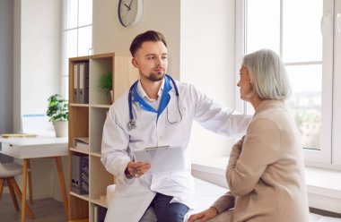 Erkek doktor ya da hemşire hastane ofisinde üst düzey bir kadın hastaya danışmanlık yapıyor. Ziyaret, sağlık hizmetleri ve yaşlıların bakımı, tıbbi bakımın önemi.