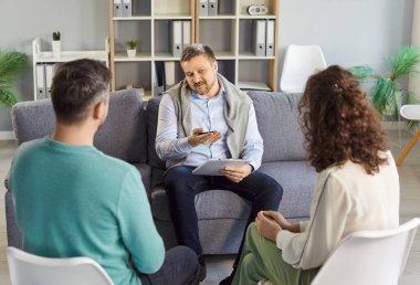 Sandalyeye oturup psikolog tavsiyesi dinleyen genç bir çift sorunları çözmeye ve danışmanlık bürosunda çözüm bulmaya çalışıyor. Aile terapisi, ilişki ve akıl sağlığı konsepti.