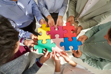 Bir grup iş adamı yapboz yapıyor. Kesilmiş çekimler. Ofis ekibi parçaları birleştirip eşleşme arıyor. İşbirliği, yardım, destek, takım çalışması kavramı