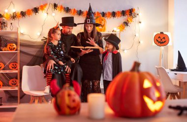 Cadılar Bayramı yaklaşıyor. Anne, baba ve iki çocuk sihirli kitap okurken süslenmiş bir odada oyulmuş balkabaklarıyla dikilip 31 Ekim 'de gizemli bir tatilin tadını çıkarıyorlar. Kostüm giyiyorlar.