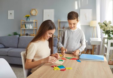 Mutlu neşeli çocuklar evdeki oturma odasında oturan ahşap geometrik figürler topluyor. Çocuklar erkek ve kız birlikte eğitim oyunu oynuyorlar. Eğitim ve aile eğlencesi.