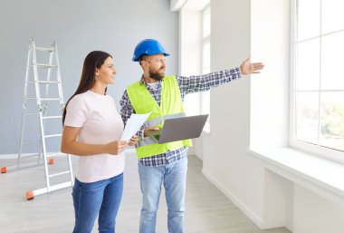 Profesyonel mimari mühendisi ve kadın apartman sahibi pencereden dışarı bakıyor ve yeni binalar hakkında konuşuyor. Dizüstü bilgisayarı olan erkek müteahhit, ev inşaatı prensiplerini genç kadınlara açıklıyor