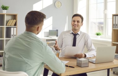 İki gülümseyen iş adamı iş yerinde oturmuş mali raporları tartışıyorlar. Erkek şirket işverenleri yeni projeler düşünüyor, şirketleri analiz ediyorlar. Takım çalışması konsepti.