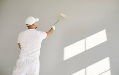 Bina müteahhitinin beyaz elbiseli, elinde boya silindiriyle boş odada fotokopi alanı olan gri duvarı boyadığını gördüm. Erkek ressam apartman onarımı ve tadilat yapıyor..