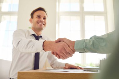 İki mutlu gülümseyen adam ofiste oturmuş başarıyı kutluyor, iyi bir anlaşma yapıyor, iş başarısı, kontrat imzalıyor ya da yeni bir çalışanı işyerlerinde selamlıyor..