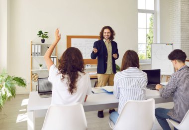 Lise öğrencileri ders sırasında sınıfta dizüstü bilgisayarlarıyla sıralarında oturuyorlar. Kız, okul öğretmenine cevap vermek için elini kaldırıyor. Okula dönmek, eğitim kavramı..