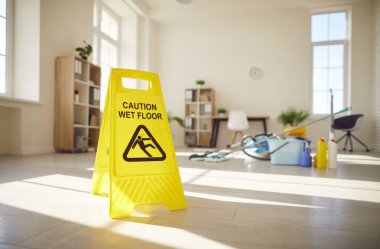 Tedbir amaçlı ıslak tabela, çeşitli temizlik aletleri, eşyalar ve arka planda boş bir oda ya da ofis olan malzemeler. Temizlik, temizlik ve ev işi konsepti.