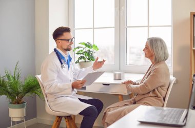 Genç erkek, profesyonel doktor, kıdemli kadına, yaşlı erkek hastaya danışmanlık yapıyor, yaşlı kadın müşteriyle tıbbi muayene, yaşlılık tedavisi ve sağlık kontrolü için konuşuyor. 