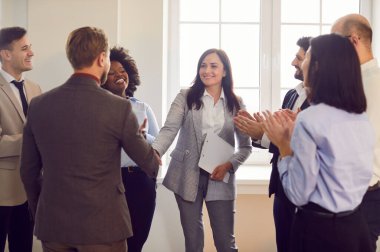 Şirket çalışanları başarıyı kutlamak için el sıkışıyor, anlaşma yapıyor, iş başarısı sağlıyor ya da sözleşme imzalıyor. Bir grup iş adamı bir toplantıda iş arkadaşlarını alkışlıyor..