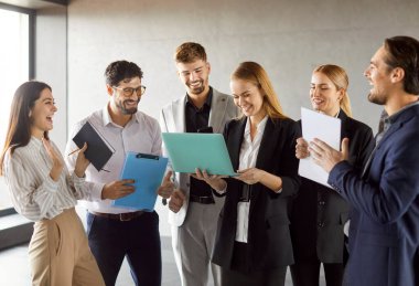 İş ortakları iş toplantısı yapıyor, pazarlama stratejilerini tartışıyor, bazı kağıtları ve dizüstü bilgisayarları tutuyor, fikirleri paylaşıyor, resmi kıyafetler giyiyor, gelecek iş etkinliğine hazırlanıyor.