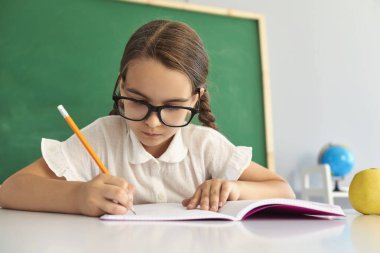 Öğrenci okulu. Akıllı liseli kız sınıfta deftere bir şeyler yazıyor. Çocuk öğrenciler için eğitim koleji lyceum 'u.