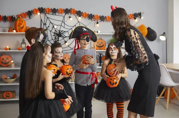 Cadılar Bayramı partisinde ürkütücü kostümlü mutlu çocuklar şaka mı şeker mi? Anne, komşu ya da öğretmen korkunç korsanlar, canavarlar, cadılar ve vampirler gibi giyinmiş çocuklara şeker veriyor.