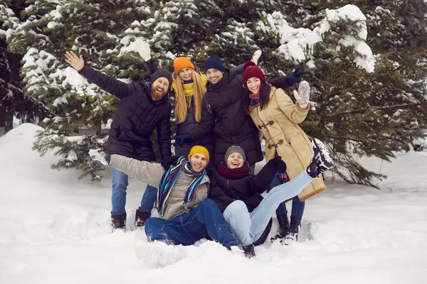 Güzel kış gününde eğlenen ve taze karın tadını çıkaran bir grup mutlu gencin portresi. Sıcak giysili gençler kameranın önünde gülüp eğleniyorlar..