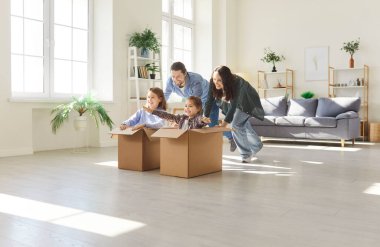 Neşeli aile ve çocuklar birlikte eğleniyorlar. Çocuklar kutulara biniyor, oynuyor ve eğleniyorlar. Neşeli ve rahat bir ev ortamında ev eğlencesi ve kaliteli zaman geçirmek.