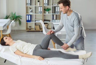 Erkek terapist ya da fizyoterapist kadın dizinin tedavisini yapıyor, fiziksel yaralanmadan sonra tıbbi bakım sağlıyor. Özel klinikte rehabilitasyon gören memnun bir kadın, sonuçlardan memnun.