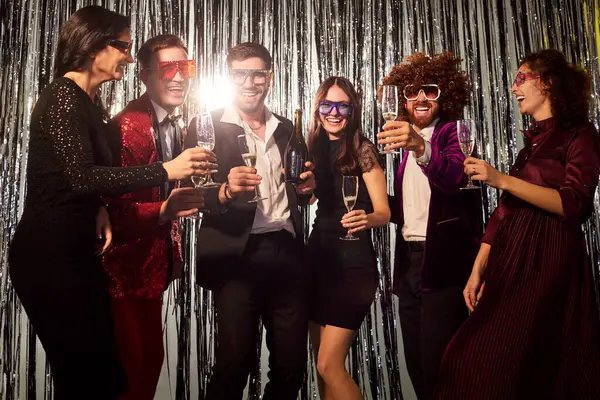 Bir gece kulübündeki bir partide şampanya bardaklarıyla dans eden bir grup neşeli arkadaş. Eğlenceli bir bayram kutlaması, canlı bir atmosferde müzik, eğlence ve eğlence içerir..