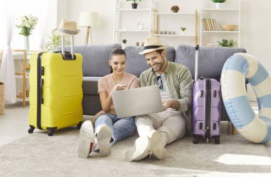 Mutlu yeni evli çiftimiz online uçuş biletleri, turist bavulları toplanmış, plajda tekerlekli bavullar şapka, güneş gözlükleri takın, turizmden, seyahatten, tatil, balayı planından keyif almaya hazır olun.