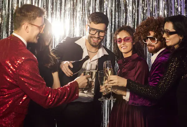 Gece kulübündeki arkadaşlar, tatil arkadaşları şampanya şişesi dolduran insanlar, parti gecesi için kostüm giyen insanlar şirket diskosu, geleneksel kulüp toplama eğlencesi, dans salonu diskoteği.