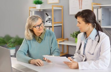 Bakıcı hemşire, doktor, doktor, hekim, yaşlı bir kadınla klinikte yaşlı bir kadına tıbbi ziyaret, bakım ve tıbbi tedavi süresince yardım etmek için yaşlı bir kadınla konuşmak,