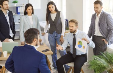 Bir grup neşeli iş adamı çalışma masasında oturmuş iş ve ofis projelerini tartışıyorlar. Şirket çalışanları, konferans sırasında erkek meslektaşlarını dinlerler..