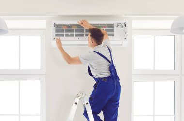 İşçi ya da elektrikçi evdeki havalandırma sistemini inceliyor, özel bir aletle onarım ya da onarım işi yapıyor. Ev HVAC sistem servisine odaklanıldı.