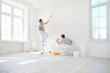 Erkek profesyonel ressamlardan oluşan bir ekip, bir ev veya ofisteki yenileme projesi sırasında duvar boyamak için birlikte çalışıyor. İnşaat alanındaki alanı geliştirmek için takım çalışması ve adanmışlık.