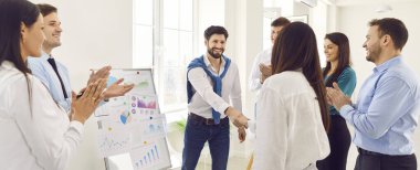 Mutlu gülümseyen şirket çalışanları modern ofiste el sıkışıyorlar. İş adamları, bir toplantıda meslektaşlarıyla başarılı bir ortaklığa sevinerek alkışladılar. Pankart.