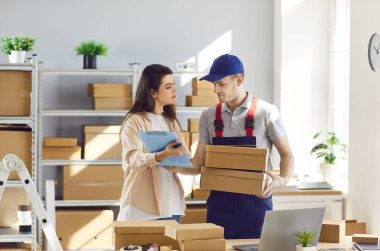 Depoda lojistik ya da dağıtım merkezindeki kadın küçük işletme sahibiyle çalışan teslimat işçisi bir müşterinin siparişini hazırlıyor. Stok envanteri.