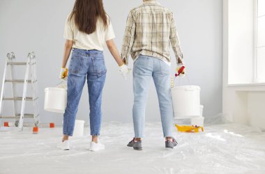 Ev tadilatı sırasında bir karı kocanın birlikte duvar boyadığı görüntüler. Çift yan yana çalışarak yeni dairelerinin inşası ve dekorasyonuna katkıda bulunuyor..