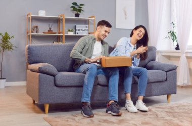 Paketi açan, mutlu olmak için karton kutuyu açan genç çift, uzun zamandır beklenen paketi aldı, hızlı, kolay, hızlı posta paketi teslimatı, güvenilir posta kurye servisi, çevrimiçi market siparişi