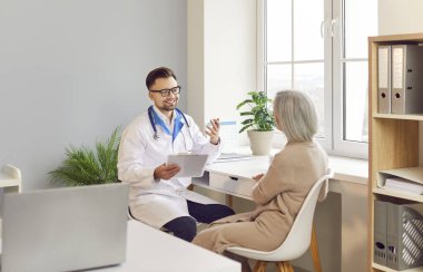 Pozitif doktor ya da hemşire hastane ziyareti sırasında yaşlı bir hastayla konuşuyor. Tıbbi uzman, hastalara sağlık hizmeti ve terapi sunuyor..