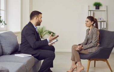 Elinde mikrofon tutan ve bir kadınla televizyon programı için röportaj yapan bir muhabir. Talk show ya da haber programı, sunucu konuğa sorular soruyor. Röportaj ya da halkla ilişkiler.