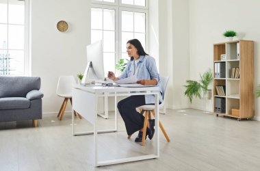 Ofisinde çalışan kadın muhasebeci, muhasebeci, denetçi ya da sekreter. Genç bir kadın masasında oturuyor, belgelerle uğraşıyor ve modern bir bilgisayar kullanıyor.