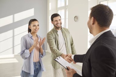 Genç bir çift ve emlakçı, emlakçı, bir kira, satın alma ve satış sözleşmesi imzalıyorlar. Karı koca bir daire, ev, mutlu bir aile, gayrimenkul satın alıyorlar..