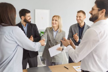 İş adamları sözleşme pazarlığı için buluşur, anlaşma yapar, işbirliği için birbirlerine teşekkür eder ve el sıkışırlar. Gülümseyen kadınlar erkeklerin alkışladığı gibi tokalaşıyorlar. Profesyonel ortaklık kavramı