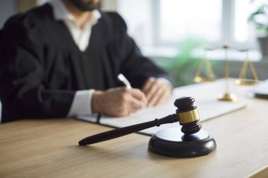 Tanımlanamayan hâkim imajı adil karar ve kurallardan geçer, kağıtları imzalar, ön planda tokmağın yanında poz verir, adliyede poz verir. Kanun ve düzen, yargı konsepti. 