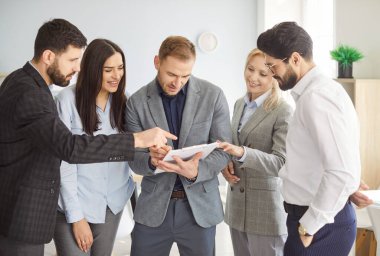 Proje detaylarını tartışan iş grubu, çeşitli meslektaşlar ofiste toplanıyor, ortak bir görev üzerinde çalışıyorlar, satış müdürü ve şirket müşterileri yeni kağıt belgelerini kontrol ediyorlar 