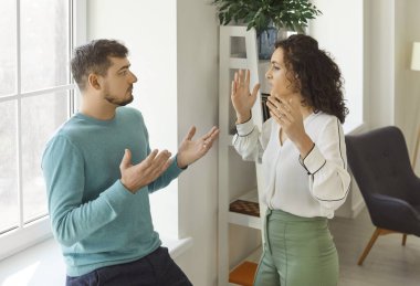 Öfkeli genç bir çift birbirleriyle tartışıyor. Sinirli kadın el kaldırırken duygusal adam karşılık veriyor. Gergin sohbet, ilişki çatışması, yanlış anlaşılma ve stres.