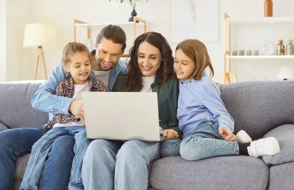 Küçük çocukları olan mutlu ebeveynler yeni dizüstü bilgisayarlarıyla eğleniyorlar, rahat bir oturma odası, çocukları olan sevgi dolu bir çift evde bilgisayar kullanıyor, aile birlikte alışveriş yapıyor, internetten izliyor. 