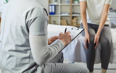 Terapist hastayla istişare eder, bacak, eklem ve diz için rehabilitasyon ve fizyoterapi hakkında konuşur, profesyonel bir ortamda özen ve destekle fiziksel iyileşmeye odaklanır..