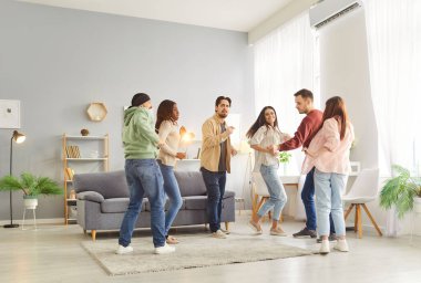 Mutlu gülümseyen, neşeli genç arkadaşlar. Günlük kıyafetler içinde erkekler ve kadınlar ev partisinde birbirleriyle dans ediyorlar. İnsanlar oturma odasında eğleniyor. Birlikte vakit geçiriyorlar. İçeride toplanıyorlar..