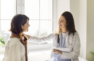 Nazik genç bayan pratisyen doktor omuz destekleyici jest kliniğinde hasta kadınla konuşuyor, sağlık sonuçlarını açıklıyor, sağlık taraması, randevu üzerine danışmanlık yapıyor, tavsiye üzerine danışmanlık yapıyor.