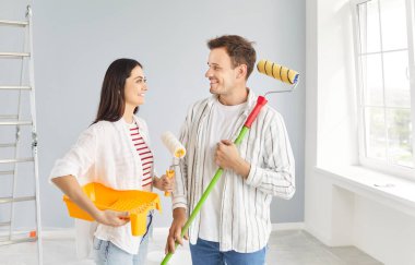 Genç çiftler yeni bir yapı planlıyorlar, boya fırçasıyla duvar boyuyorlar, odanın taşınması için işleri bitiriyorlar, bina onarımı, tadilat, yenileme, birlikte yeni bir hayata başlamak.