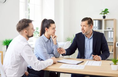 Birkaç müşteri bir ofis ortamında finans danışmanı ya da sigortacıyla görüşmüş. Yatırımları tartışmak ve yardım almak, müşteriler için önemli tavsiyelerin altını çizmek.