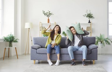 Komşuların gürültüsünden rahatsız olan genç çift, evdeki kulakları kapatıyor. Paylaşılan bir yaşam ortamında yenileme, yüksek sesli müzik veya diğer gürültülü etkinliklerin neden olduğu rahatsızlık.