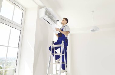 Erkek işçi ya da teknisyen, konforlu yaşam koşulları için ideal performans ve verimliliği sağlamak, ev veya ofis klimasının kurulumu, denetlenmesi ve bakımı.