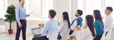 Yeni şirket personeli için sunum yapan işletme koçu, bir grup profesyonel konferans salonunda toplandı. Eğitim brifingi, resmi toplantı, seminer eğitimi, beyin fırtınası fikirleri...